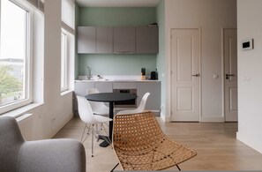 Una cocina moderna con armarios blancos, una mesa de comedor con sillas y una silla de mimbre.