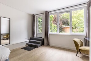 A room with a large window, a mirror, a staircase, and a chair. - Modern Ground-floor Apartment With Garden (Rotterdam)