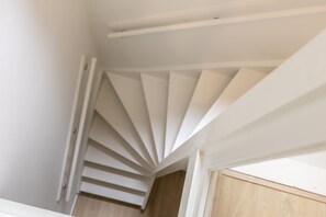 A spiral staircase in a room with white walls and a wooden floor. - Modern Lower-ground Apartment in Rotterdam West (Rotterdam)