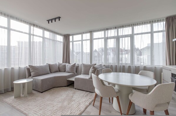 Una sala de estar moderna con un sofá modular, una mesa de comedor redonda y una mesita auxiliar.