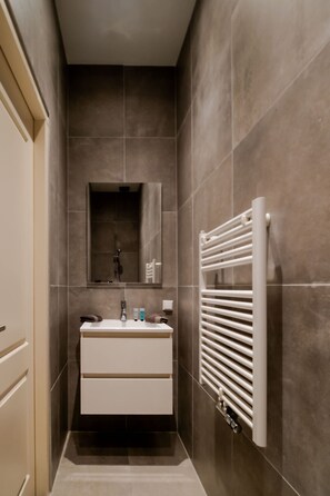 A narrow bathroom with a white sink, mirror, and towel rack. - Your Modern Retreat Close to Rotterdam City Center (Rotterdam)