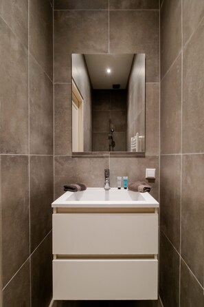 A bathroom with a white sink, mirror, and tiled walls. - Your Modern Retreat Close to Rotterdam City Center (Rotterdam)