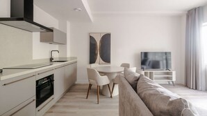 A modern kitchen with a built-in oven, a dining table with chairs, a flat-screen TV, and a large window with curtains. - Modern 2BR Apartment in Rotterdam Centre (Rotterdam)