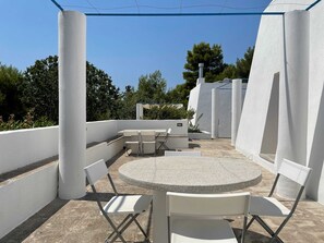 A rooftop patio with a round table and chairs, surrounded by white walls and columns. - Le Liame di Anna 10 Minutes From the sea (Salve)