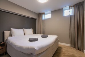 A hotel room with a large bed, two bedside tables, a window with curtains, and a ceiling light. - Spacious Blijdorp Home With 4 Double Beds (Rotterdam)