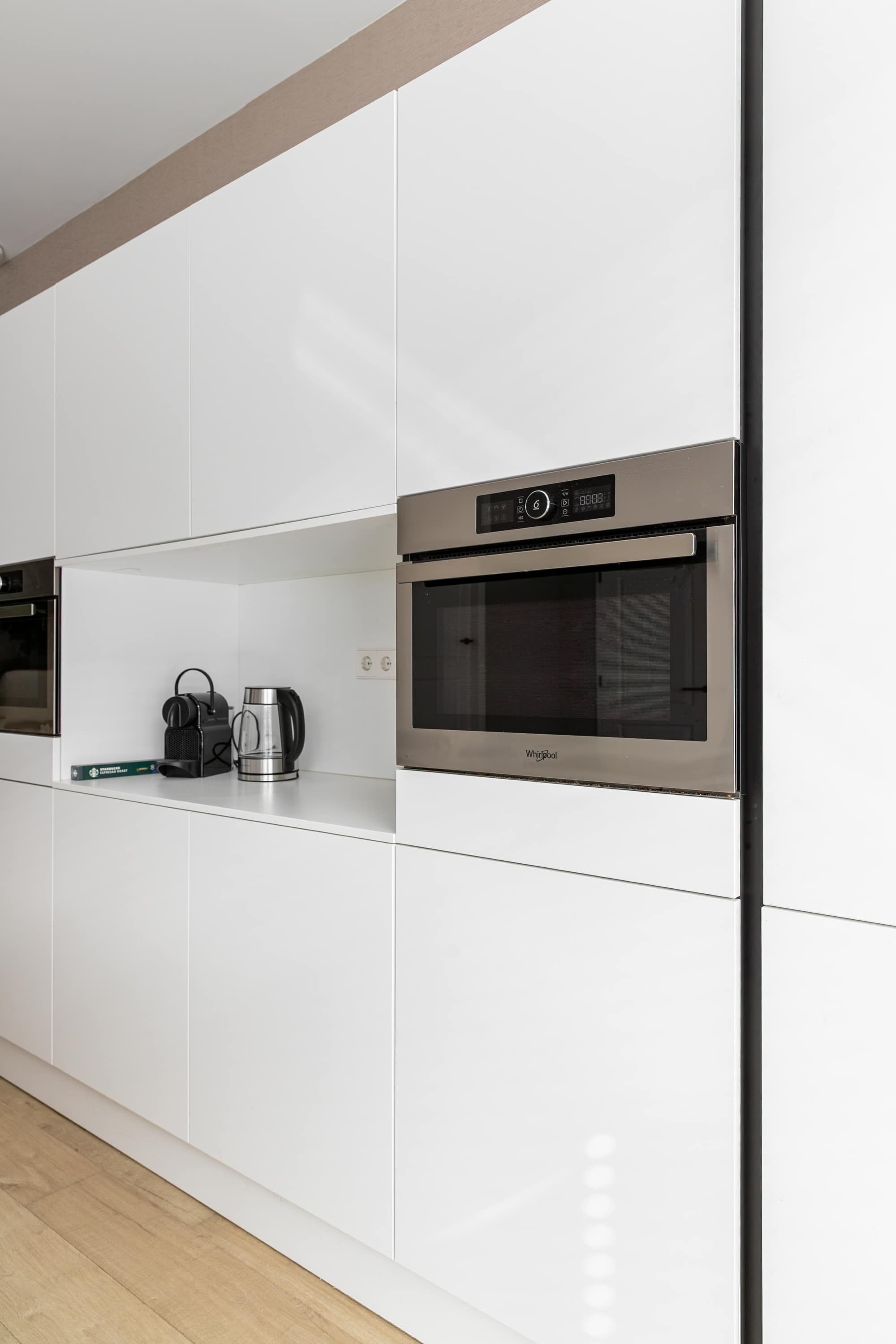 Een moderne keuken met inbouwapparatuur, waaronder een magnetron en een koffiezetapparaat.