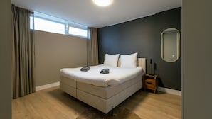 A bedroom with a bed, a bedside table, a mirror, and a window with curtains. - Spacious Blijdorp Home With 4 Double Beds (Rotterdam)