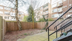 A courtyard with a wooden fence, a tree, and a staircase leading to an upper level. - Spacious Blijdorp Home With 4 Double Beds (Rotterdam)