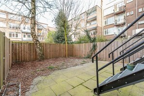 Ein Innenhof mit Holzfence, einem Baum und einer Treppe, die zu einer oberen Ebene führt.
