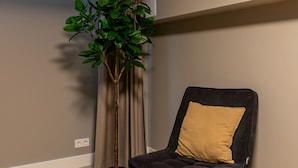 A room with a potted plant, a black chair with a yellow cushion, wooden flooring, and a window with curtains. - Spacious Blijdorp Home With 4 Double Beds (Rotterdam)