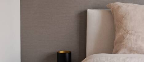 Un dormitorio con una cama, una mesita de noche y una lámpara de pared.