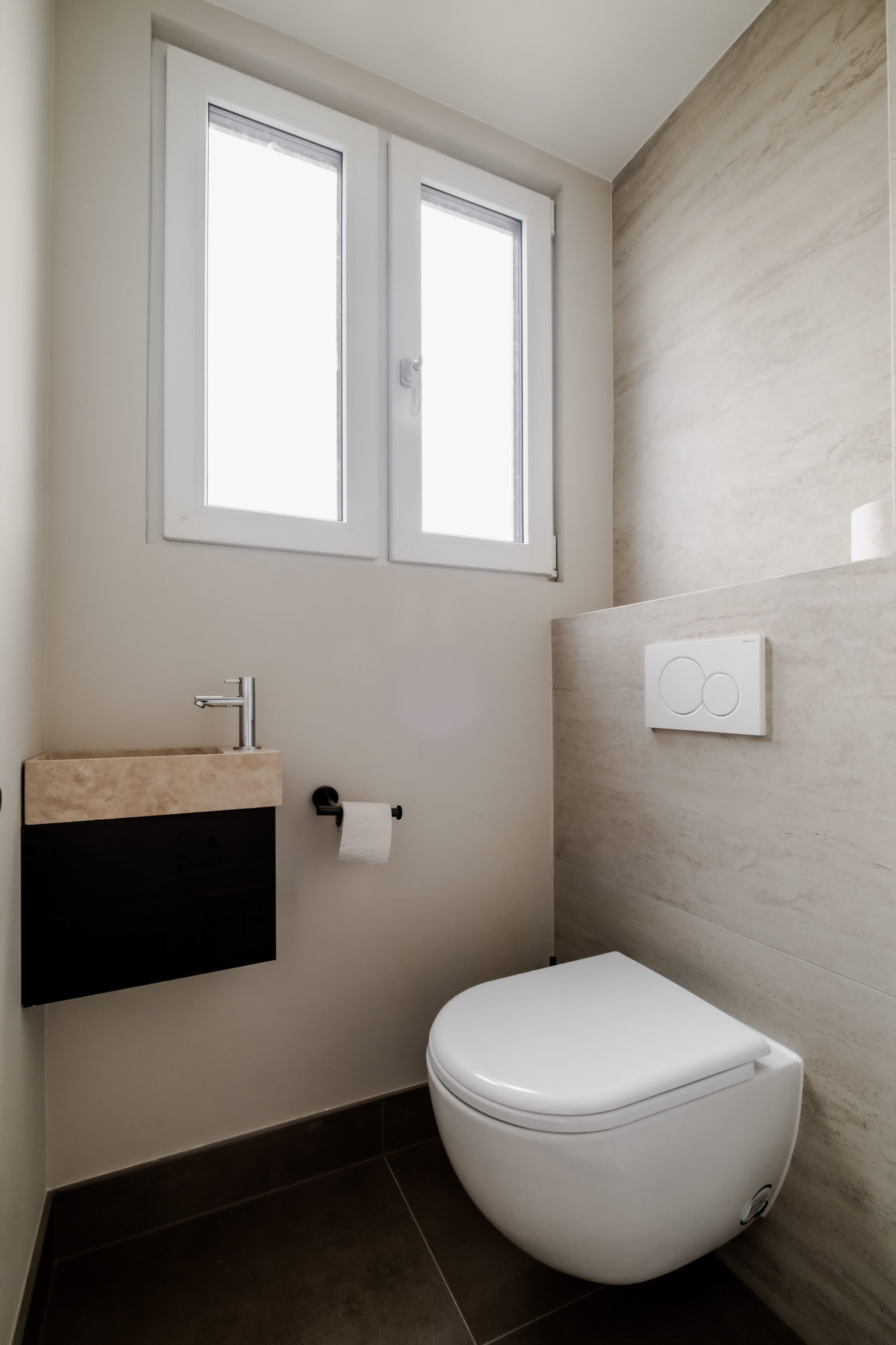 A modern bathroom with a toilet, a sink, and a window above the sink.