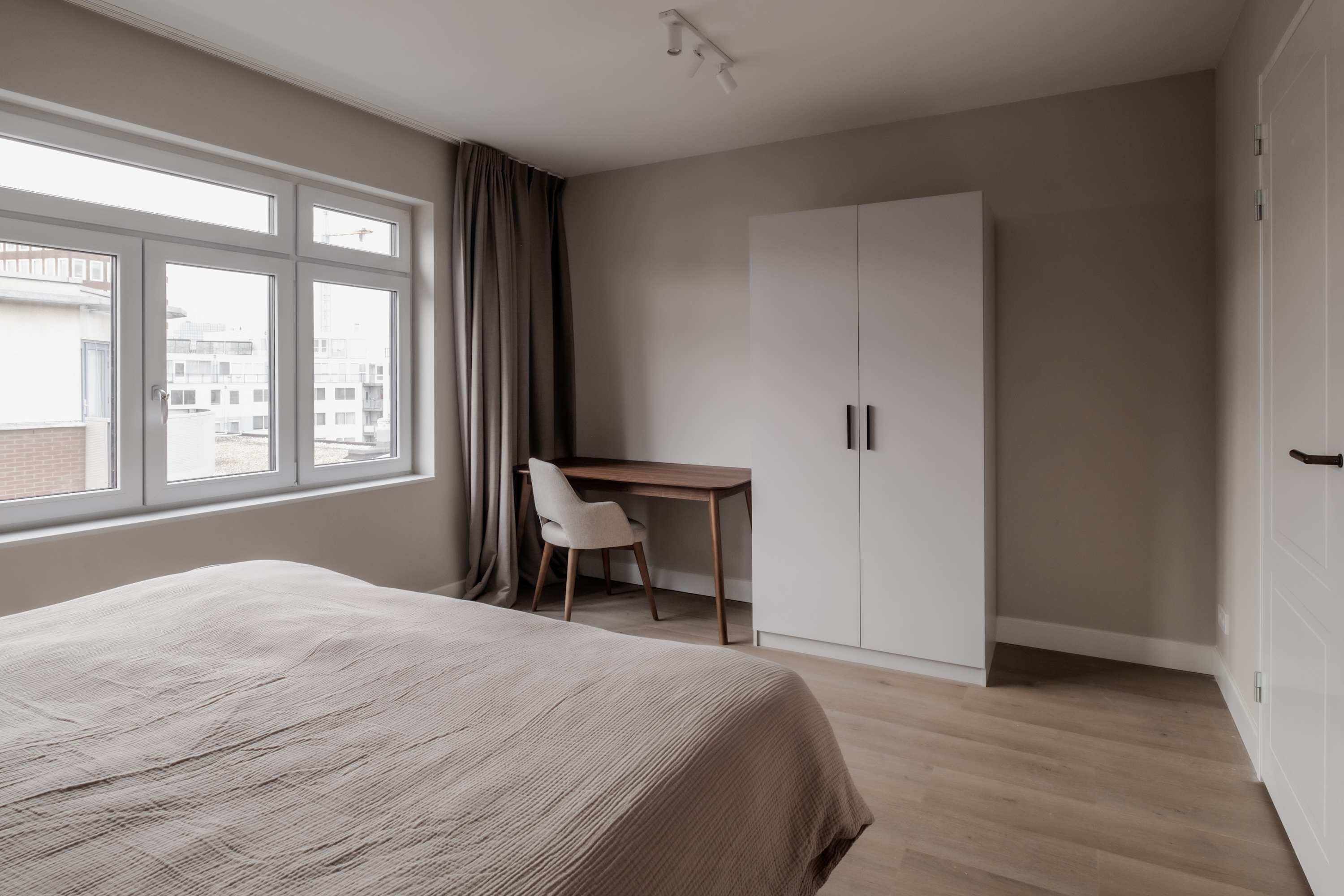 Un dormitorio con cama, escritorio y armario.