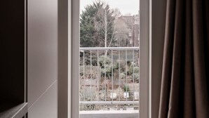 Ein Zimmer mit einem großen Fenster, Blick ins Freie und einem Vorhang.