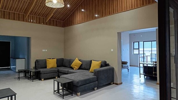 A spacious living area with a sectional sofa, a coffee table, and a pendant light. - Chiyedza Place (Juliasdale)
