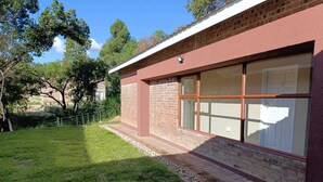 A building with a brick facade, large windows, and a grassy yard. - Chiyedza Place (Juliasdale)