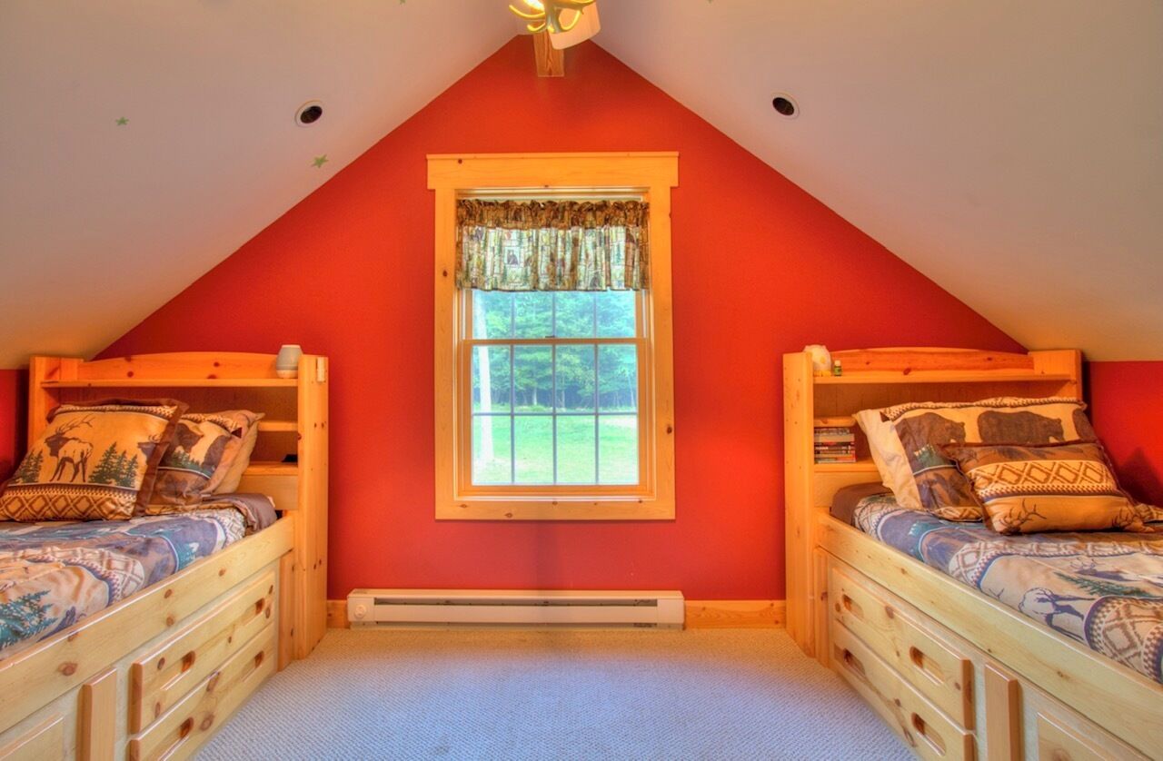 Une chambre avec deux lits en bois, une fenêtre donnant sur un beau paysage et un ventilateur de plafond.