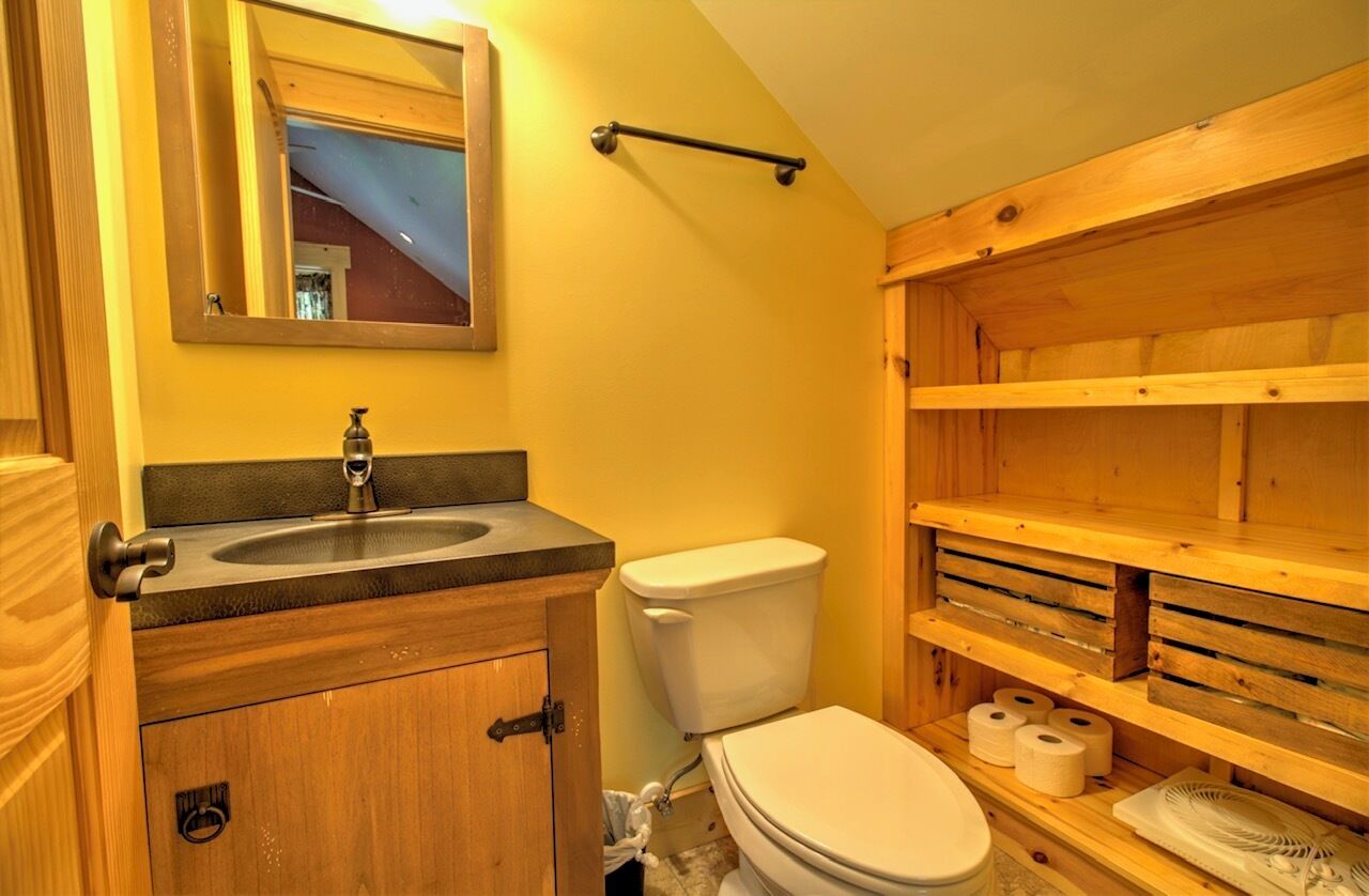 Ein Badezimmer mit einem Holzwaschtisch, einem Waschbecken, einer Toilette und einem Spiegel.