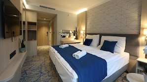 Una habitación de hotel con una cama grande, una mesita de noche, un espejo, un armario y un televisor.