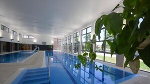 Una piscina interior con paredes de vidrio transparente, zona de la piscina en azul y escalones de acceso.