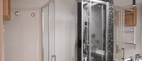 A modern bathroom with a glass-enclosed shower, a white sink, and a large mirror.