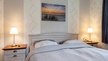 Ein Schlafzimmer mit einem Bett, zwei Nachttischen, einer Nachttischlampe, einem Wandbild und einer Wandtapete mit Muster.