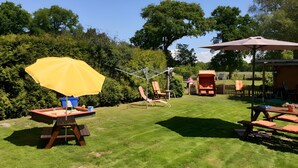 A backyard with a picnic table, a yellow umbrella, and a wooden deck. - Apartment '3 Ebenerdig' (Cuxhaven)