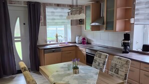 A modern kitchen with a dining table, chairs, and a window with curtains. - Apartment '3 Ebenerdig' (Cuxhaven)
