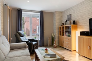 A modern living room with a sofa, a coffee table, a television, and a bookshelf. - Apartment '3 Ebenerdig' (Cuxhaven)