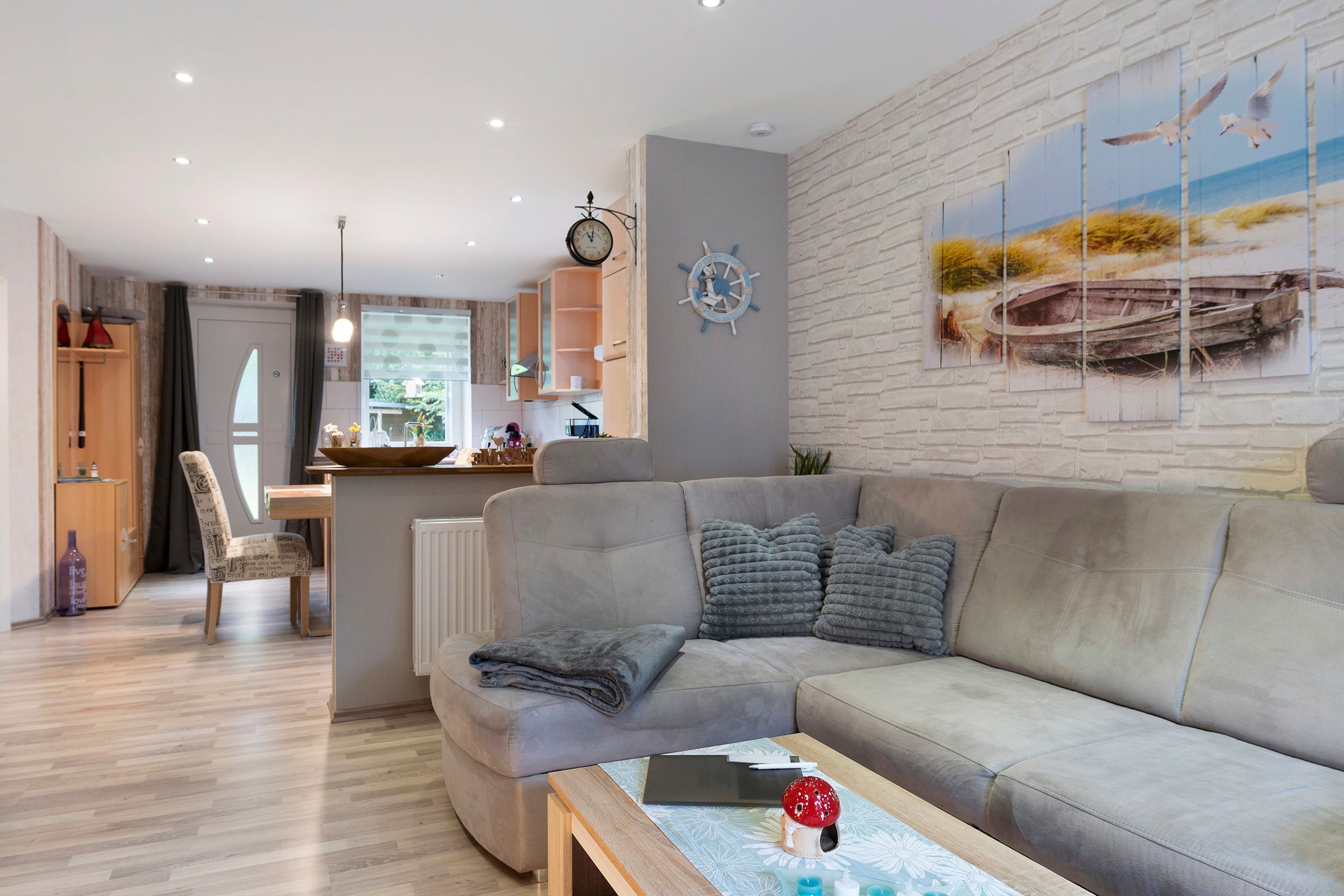 A modern living room with a grey sectional sofa, a wooden coffee table, and a wall-mounted clock.