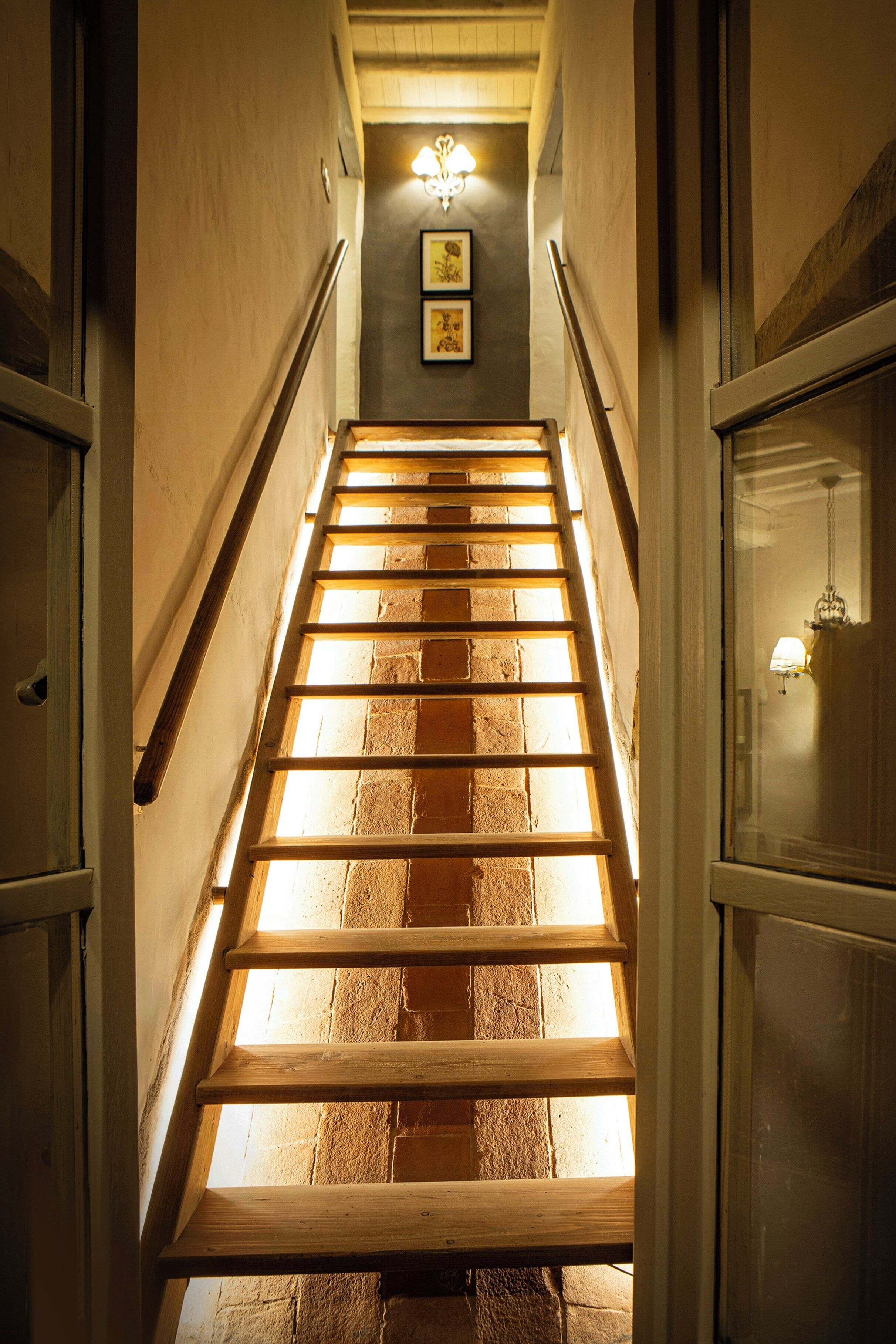Un escalier en bois avec un luminaire au sommet.