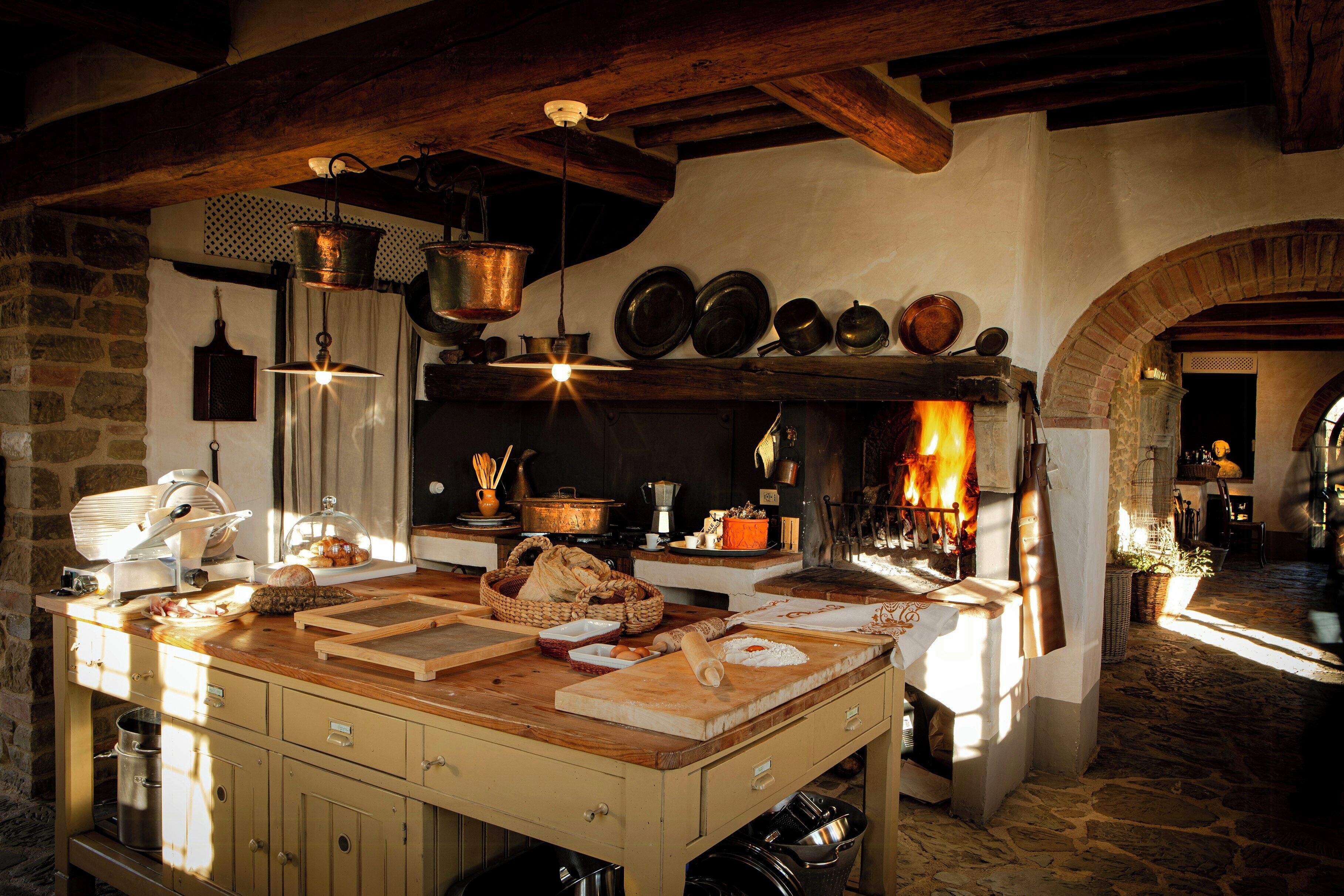 Uma cozinha rústica com uma ilha grande, panelas penduradas e um forno de tijolos.