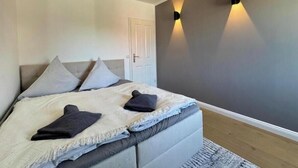 Ein Schlafzimmer mit Bett, Kissen, einer Tür und Wandleuchten.