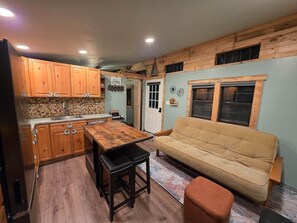 A compact kitchen with wooden cabinets, a dining table, and a sofa.