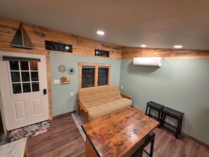 A room with a wooden ceiling, a sofa, a table, and a door.