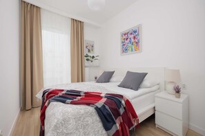 Un dormitorio ordenado con cama, mesita de noche y un cuadro en la pared.
