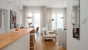 Ein modernes Wohnzimmer mit einem Holzesstisch, weißen Sofas und einem großen Spiegel.