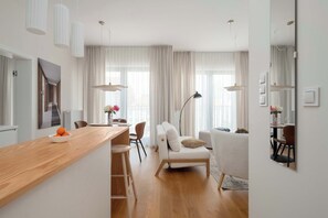 Ein modernes Wohnzimmer mit einem Holzesstisch, weißen Sofas und einem großen Spiegel.