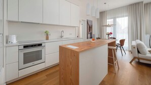 Eine moderne Küche mit weißen Schränken, einer Holzinsel und einem eingebauten Backofen.