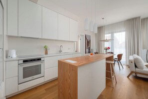 Eine moderne Küche mit weißen Schränken, einer Holzinsel und einem eingebauten Backofen.