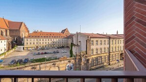 Blick vom Balkon auf einen Parkplatz und ein Gebäude im klassischen Stil.