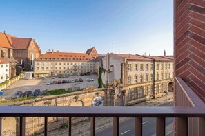 Blick vom Balkon auf einen Parkplatz und ein Gebäude im klassischen Stil.