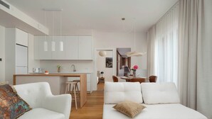 Ein modernes Wohnzimmer mit einer Couch, einem Essbereich mit Tisch und Stühlen sowie einer Küche mit Schränken und einer Arbeitsplatte.