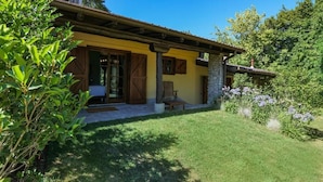 A rustic building with a yellow facade, wooden shutters, and a stone chimney.
