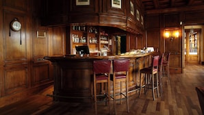 A bar area with wooden paneling, a clock, and bar stools.