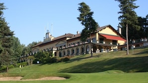 A building with multiple balconies, a clock tower, and a golf course in the foreground.