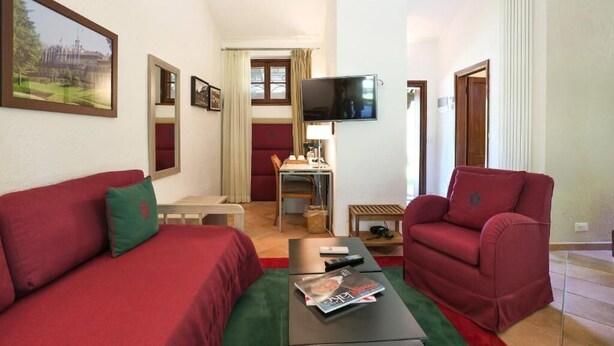 A hotel room with a bed, a sofa, a TV, and a desk with a chair.