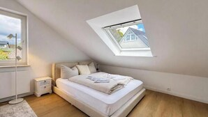 A bedroom with a skylight, a bed, a bedside table, and a floor lamp. - Sea Studio - Modern time-out right on the beach in Scharbeutz (Scharbeutz)