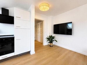A modern kitchen with white cabinetry, a black oven, and a potted plant. - Sea Studio - Modern time-out right on the beach in Scharbeutz (Scharbeutz)