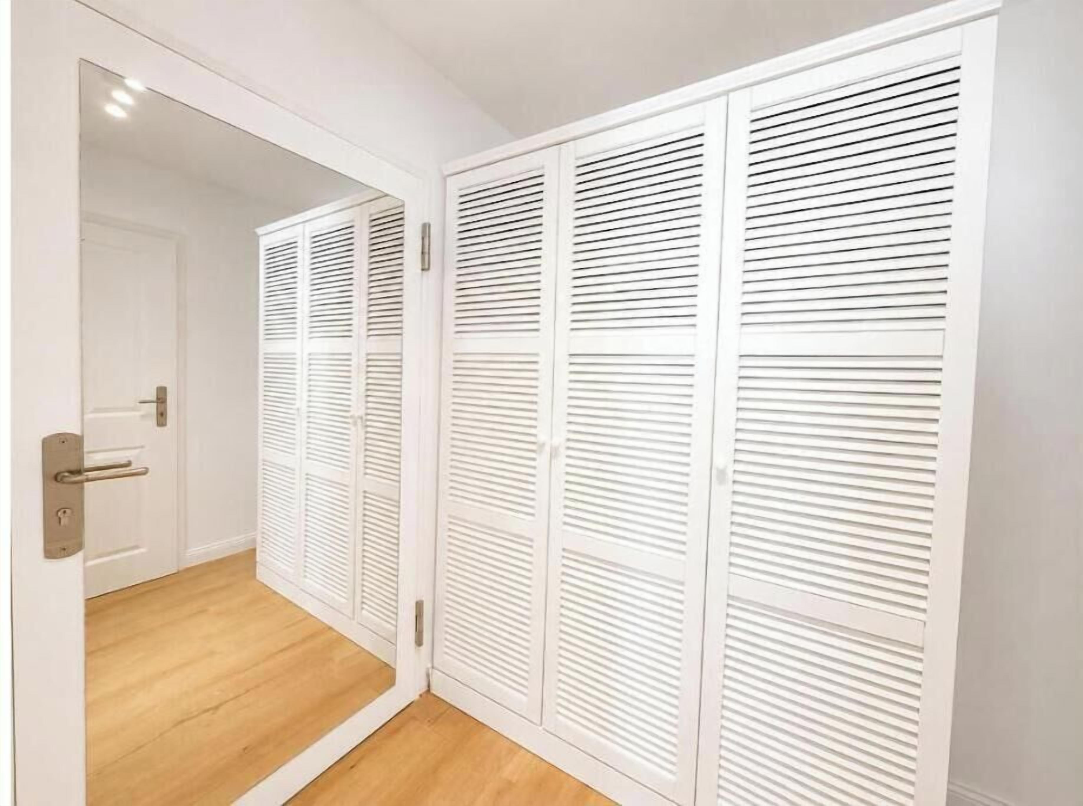 Un armario blanco con puertas correderas y piso de madera.